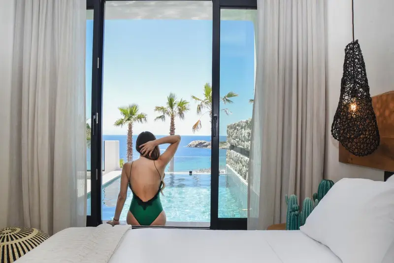 Une femme se tient près d'une piscine avec vue sur la mer.