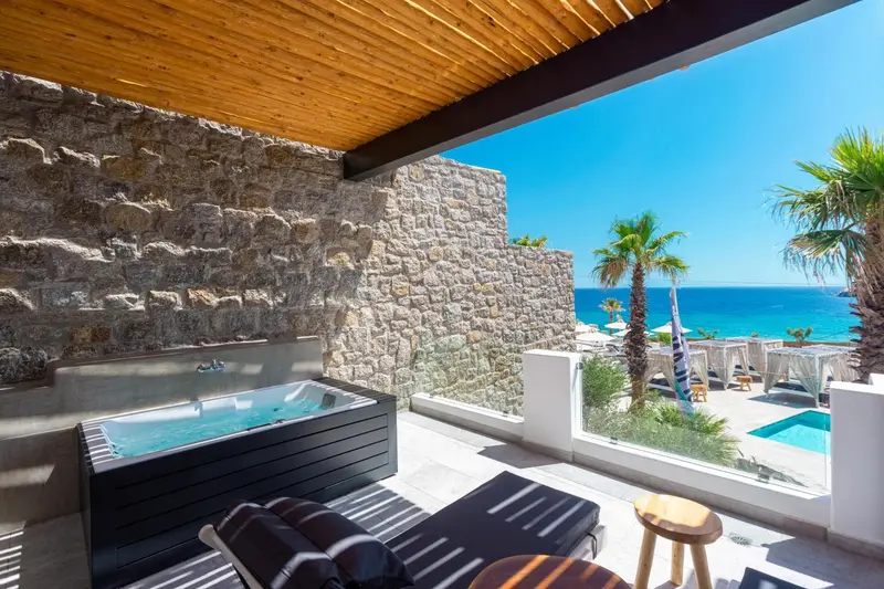 Un jacuzzi extérieur offre une vue sur la mer et la végétation.