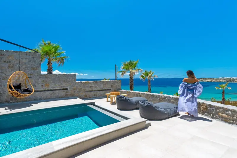 Une personne se tient près d'une piscine avec vue sur la mer.