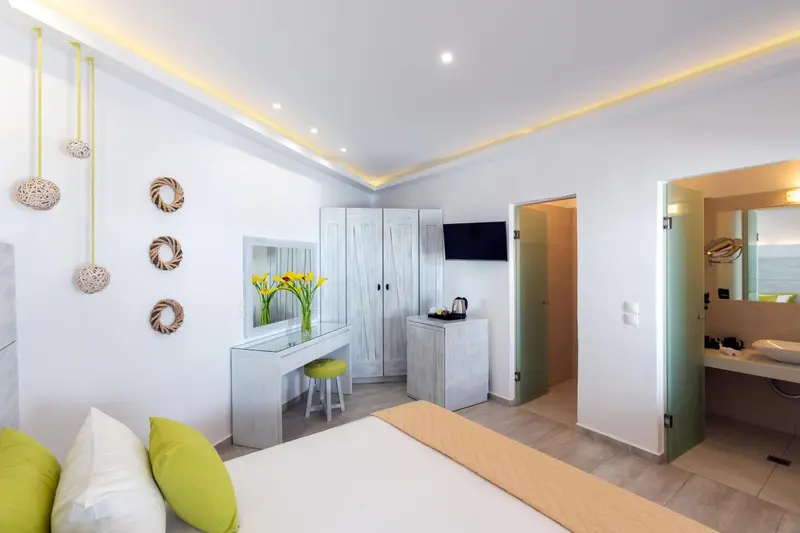 Une chambre lumineuse avec un lit, une coiffeuse et un accès à une salle de bain.