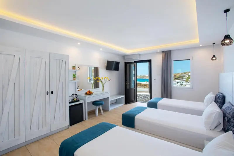 Chambre lumineuse avec deux lits simples et vue sur la mer.