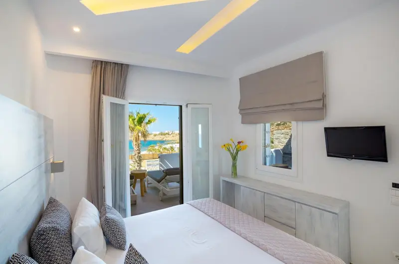 Une chambre lumineuse avec un lit fait et une vue sur la mer.