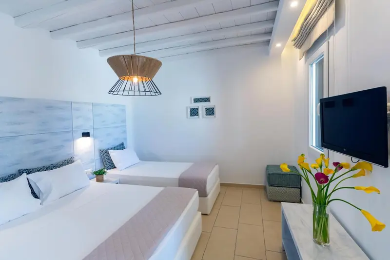 Une chambre lumineuse avec deux lits simples et une télévision.