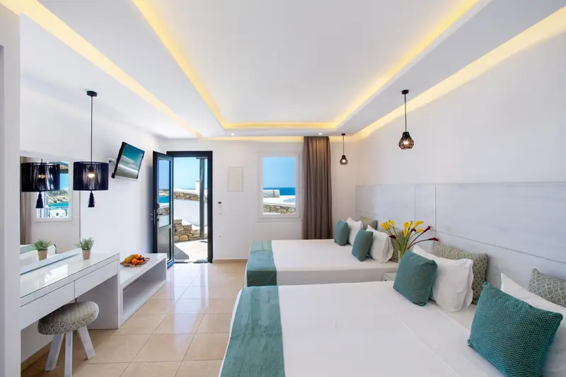 Chambre lumineuse avec deux lits simples et vue sur la mer.