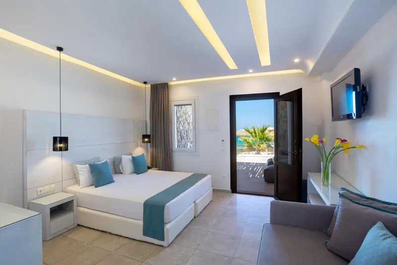 Chambre lumineuse avec un grand lit et une vue sur la mer.