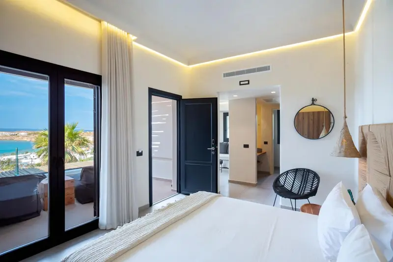 Chambre lumineuse avec un grand lit et vue sur la mer.