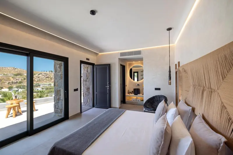 Chambre lumineuse avec un grand lit et vue sur un paysage montagneux.