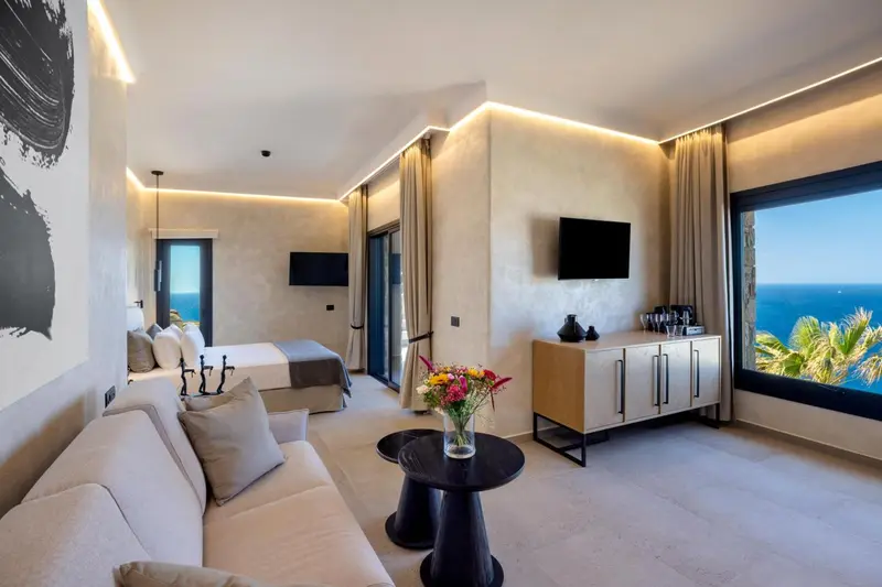 Espace de vie lumineux avec canapé, lit et vue sur la mer.