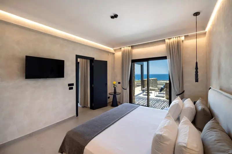 Chambre lumineuse avec un grand lit et vue sur la mer.