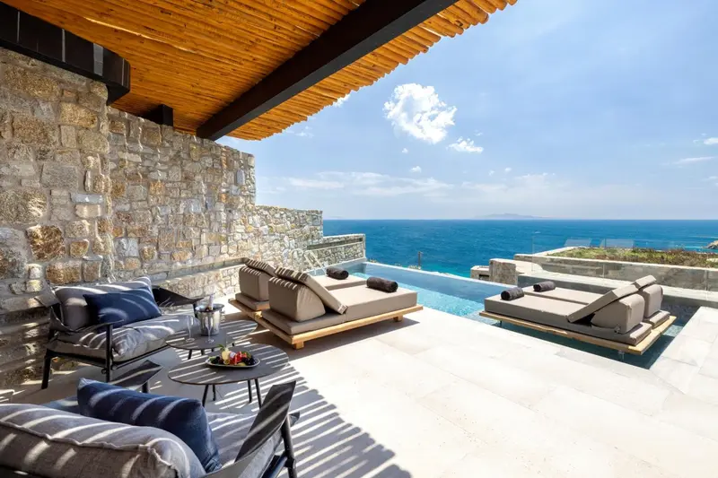 Espace de détente extérieur avec mobilier et piscine à débordement face à la mer.