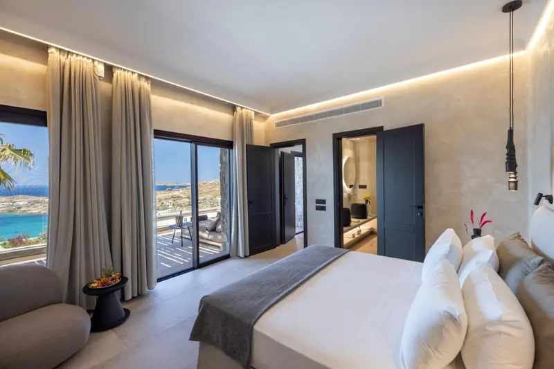Chambre lumineuse avec un grand lit et vue sur la mer.