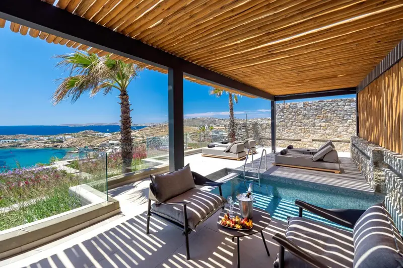 Terrasse ombragée avec salon et piscine offrant une vue sur la mer.