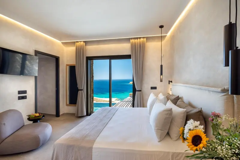 Une chambre lumineuse avec un grand lit donnant sur une vue mer.