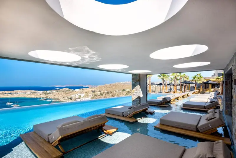 Transats alignés au bord d'une piscine à débordement avec vue sur la mer.