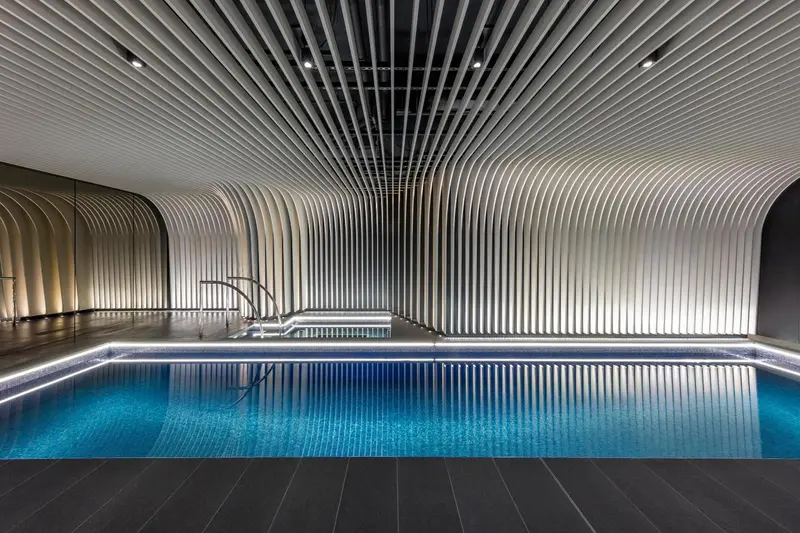 Piscine intérieure aux lignes architecturales ondulantes et éclairage moderne.