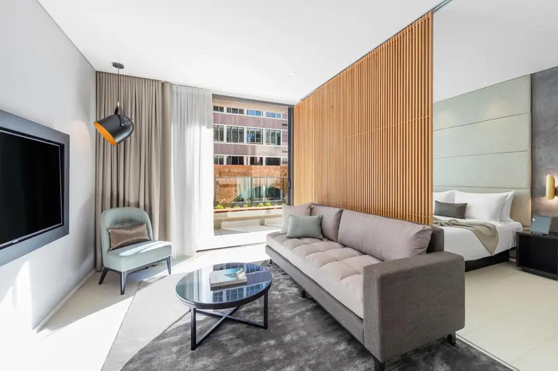 Espace de vie moderne avec canapé, fauteuil et vue sur la ville.