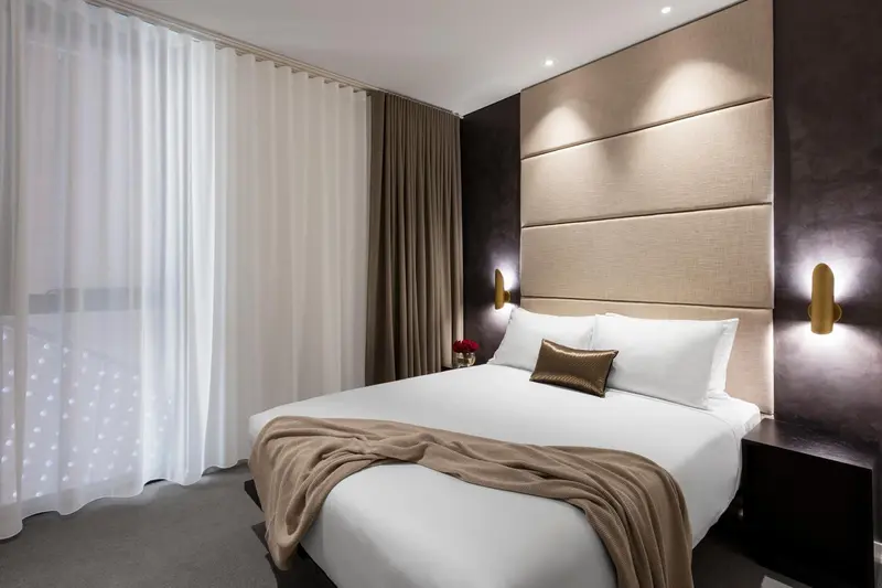 Une chambre lumineuse avec un grand lit recouvert d'une couverture et de coussins.