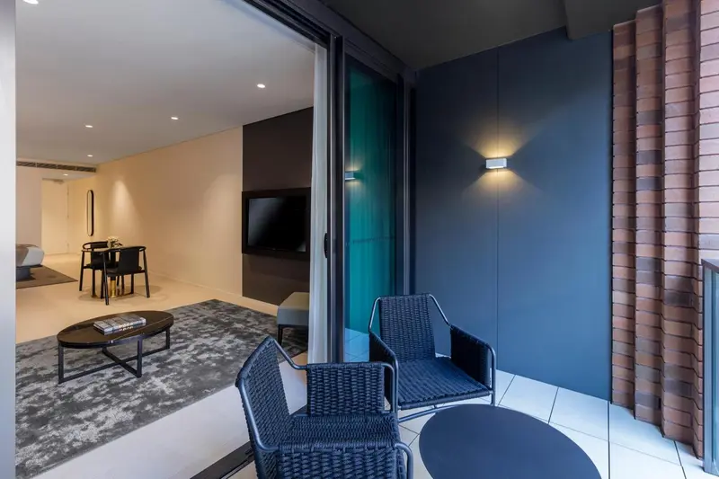 Un salon lumineux s'ouvre sur une terrasse aménagée avec des fauteuils.