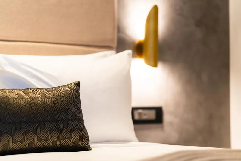 Un lit avec des oreillers blancs et un coussin décoratif.