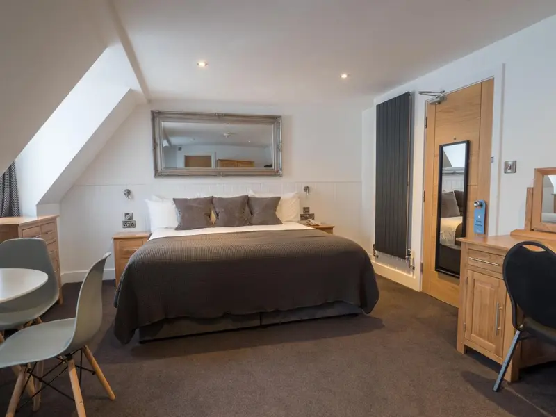 Une chambre lumineuse avec un grand lit et un coin repas.