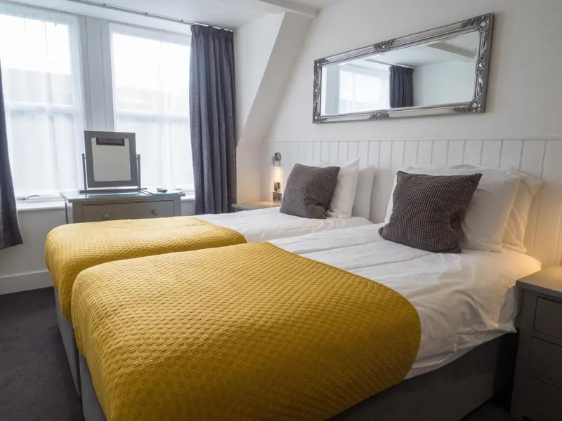 Une chambre avec deux lits simples et une coiffeuse près de la fenêtre.
