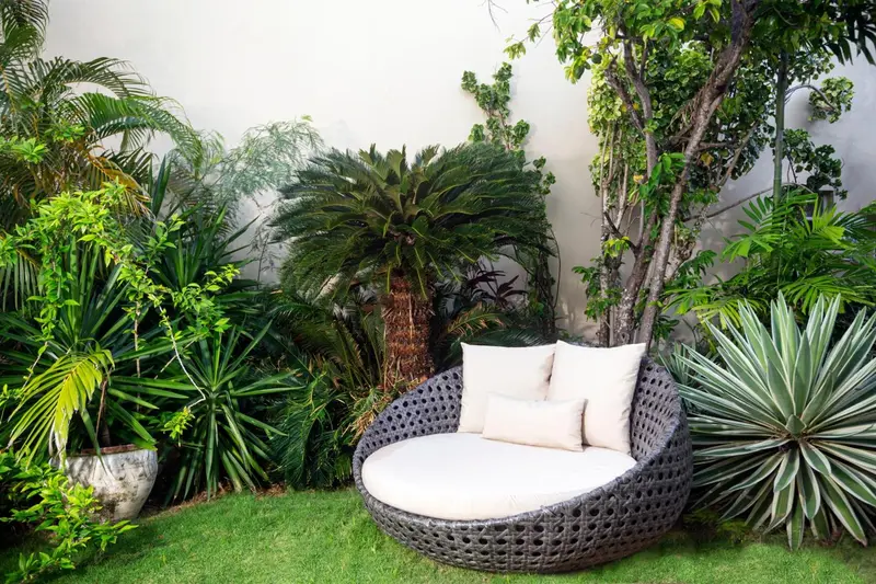 Un espace extérieur verdoyant avec un fauteuil rond et des coussins.