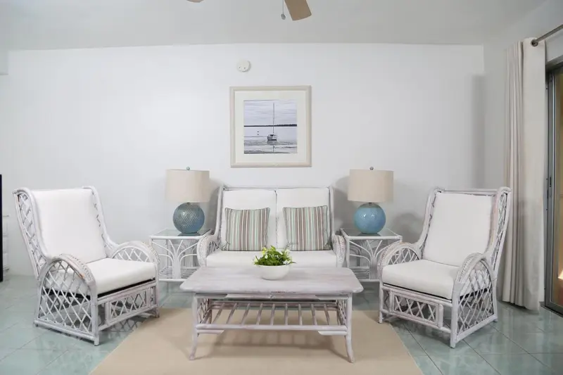 Un salon clair avec des fauteuils et un canapé en osier.