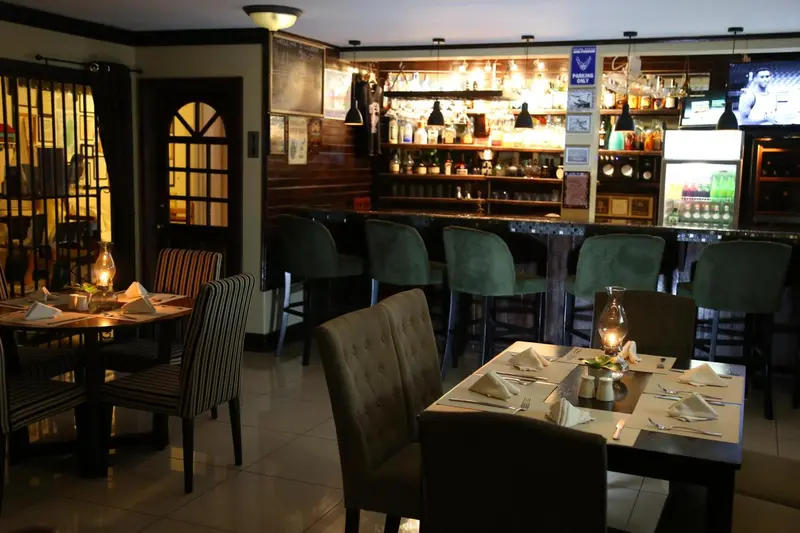 Un bar avec des tabourets et des tables éclairées par des lampes.