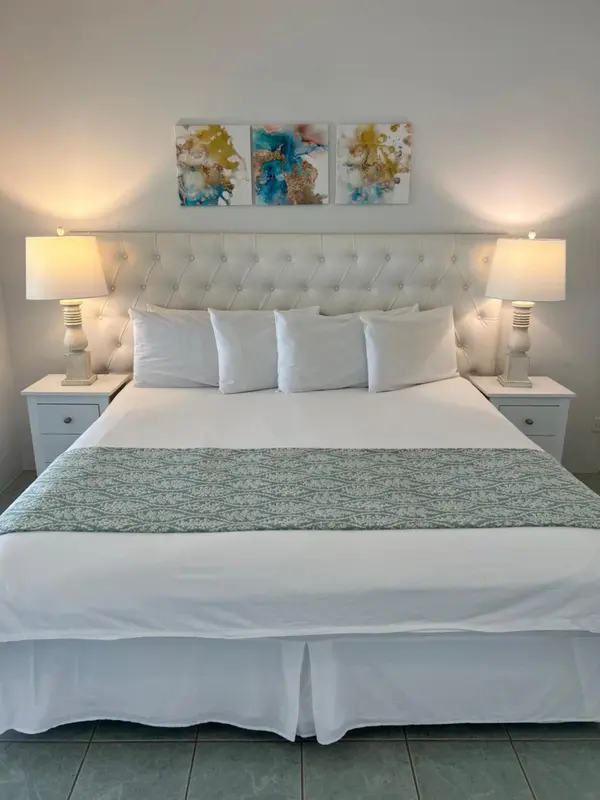 Une chambre lumineuse avec un grand lit recouvert de linge blanc.