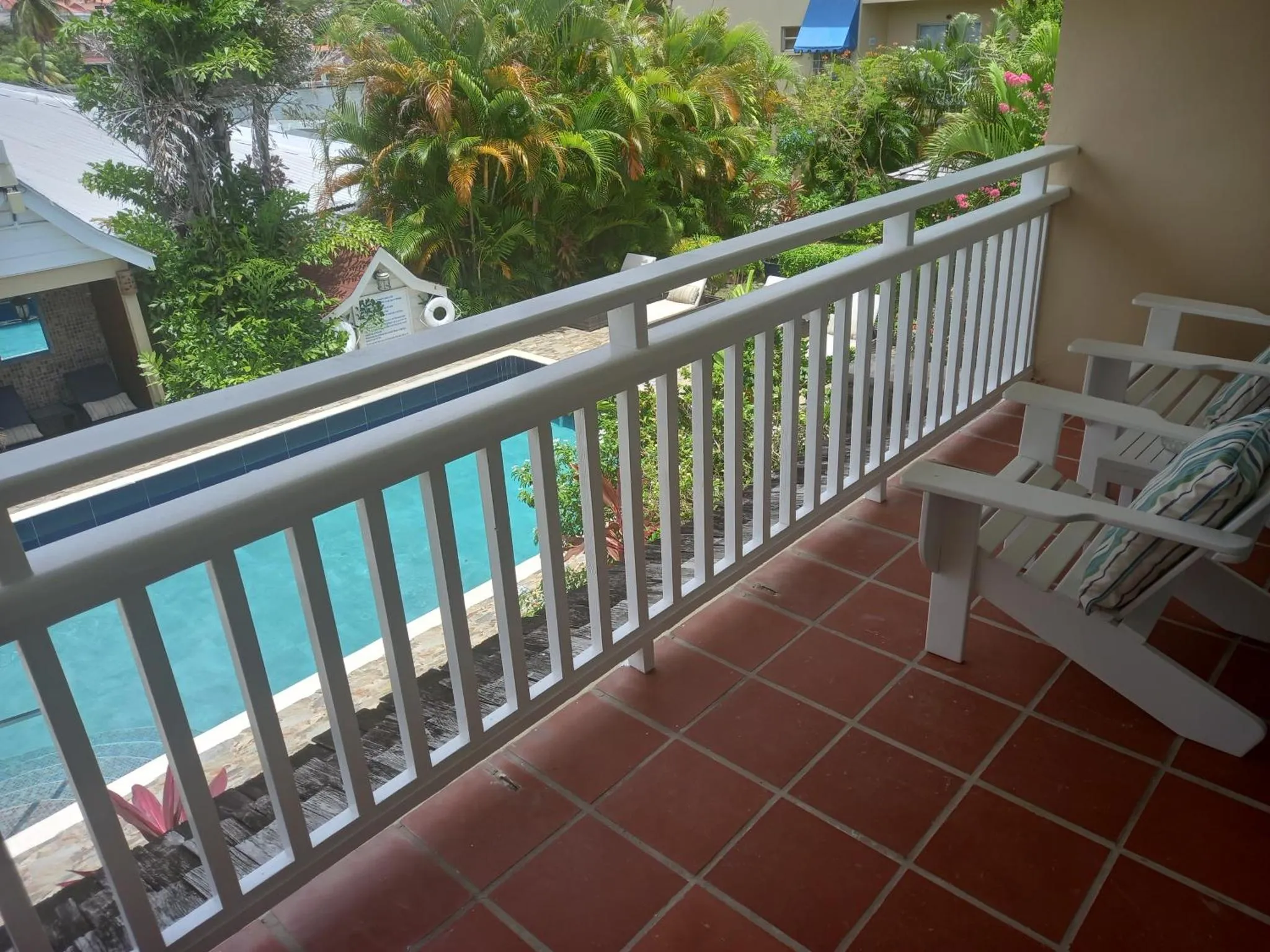 Terrasse carrelée avec transats blancs et vue sur une piscine.
