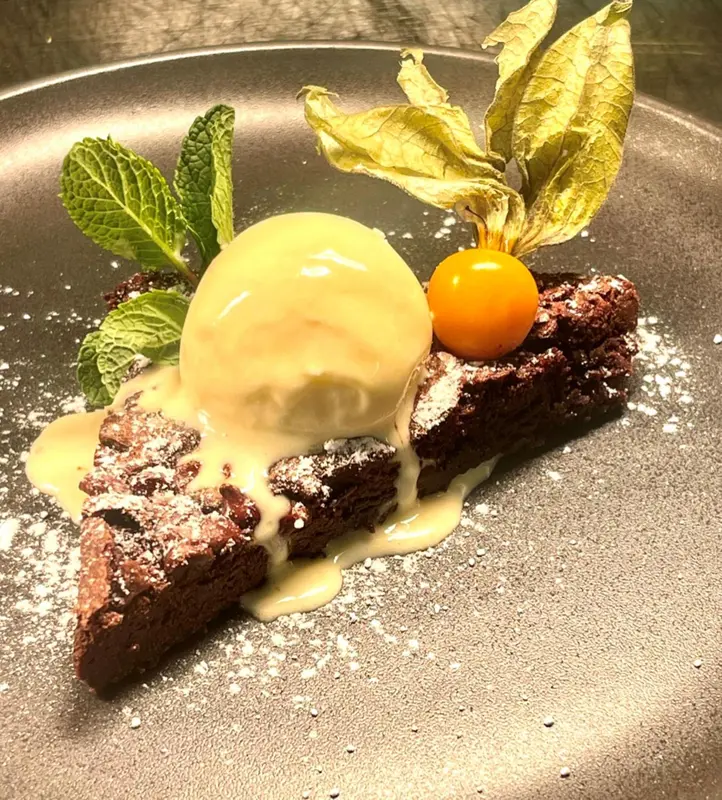 Une portion de dessert au chocolat est présentée sur une assiette grise.