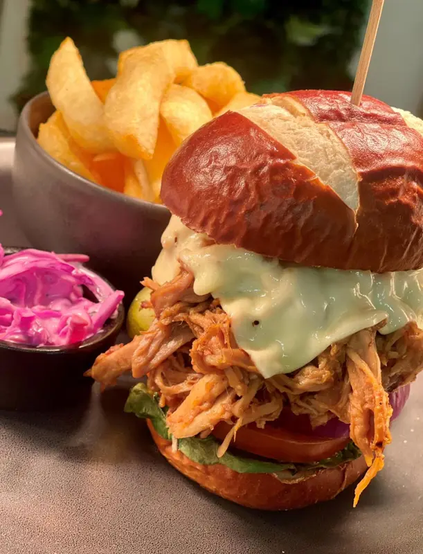 Un hamburger généreux accompagné de frites et d'une salade de chou rouge est présenté sur une table.