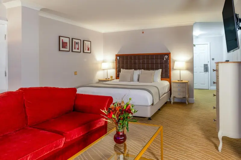 Une chambre lumineuse avec un grand lit et un canapé rouge.