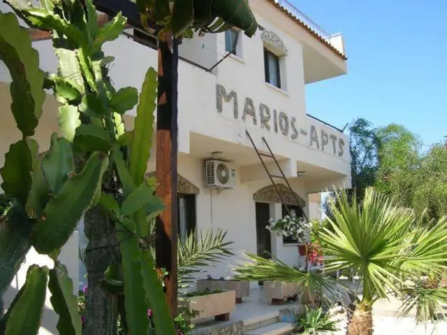 Façade blanche d'un bâtiment avec des plantes tropicales au premier plan.