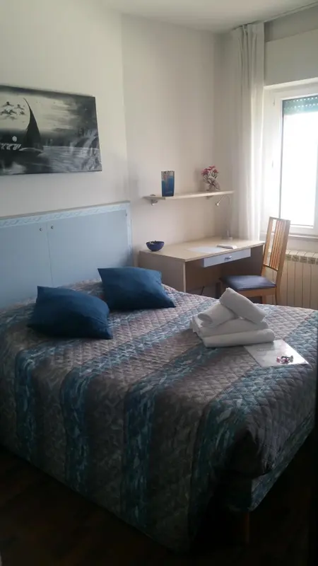 Une chambre lumineuse avec un lit double et un bureau.
