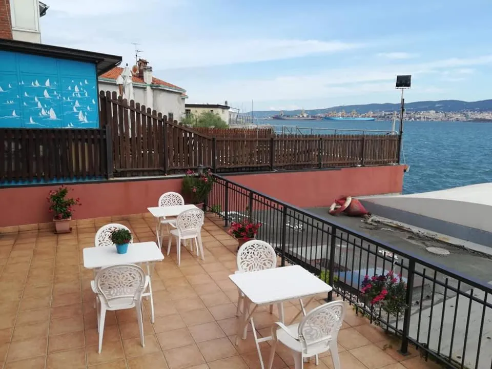 Terrasse carrelée avec tables et chaises blanches donnant sur la mer.