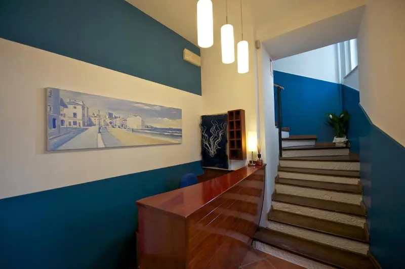 Un hall d'entrée lumineux avec un escalier et une œuvre d'art murale.