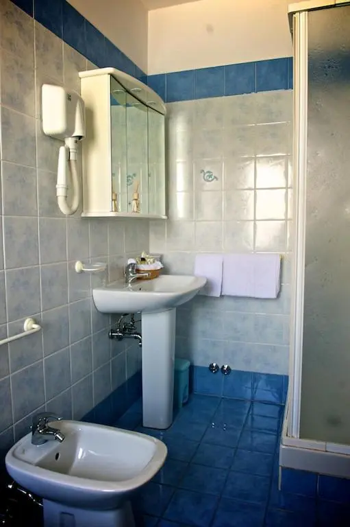 Une salle de bain claire avec lavabo, miroir et douche.