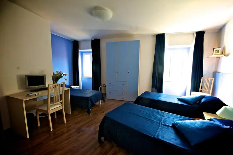Une chambre avec deux lits simples et un bureau.