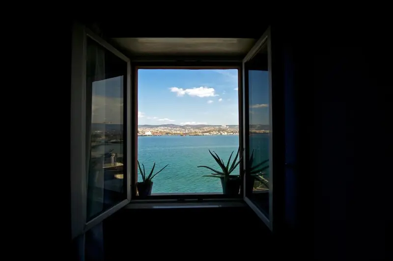 Vue sur la mer depuis une fenêtre ouverte.