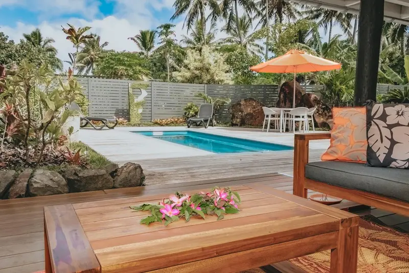 Terrasse en bois avec canapé et table basse devant une piscine.