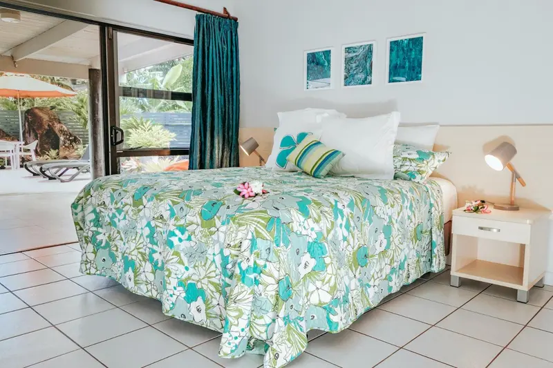 Une chambre lumineuse avec un grand lit recouvert d'une couette à motifs.