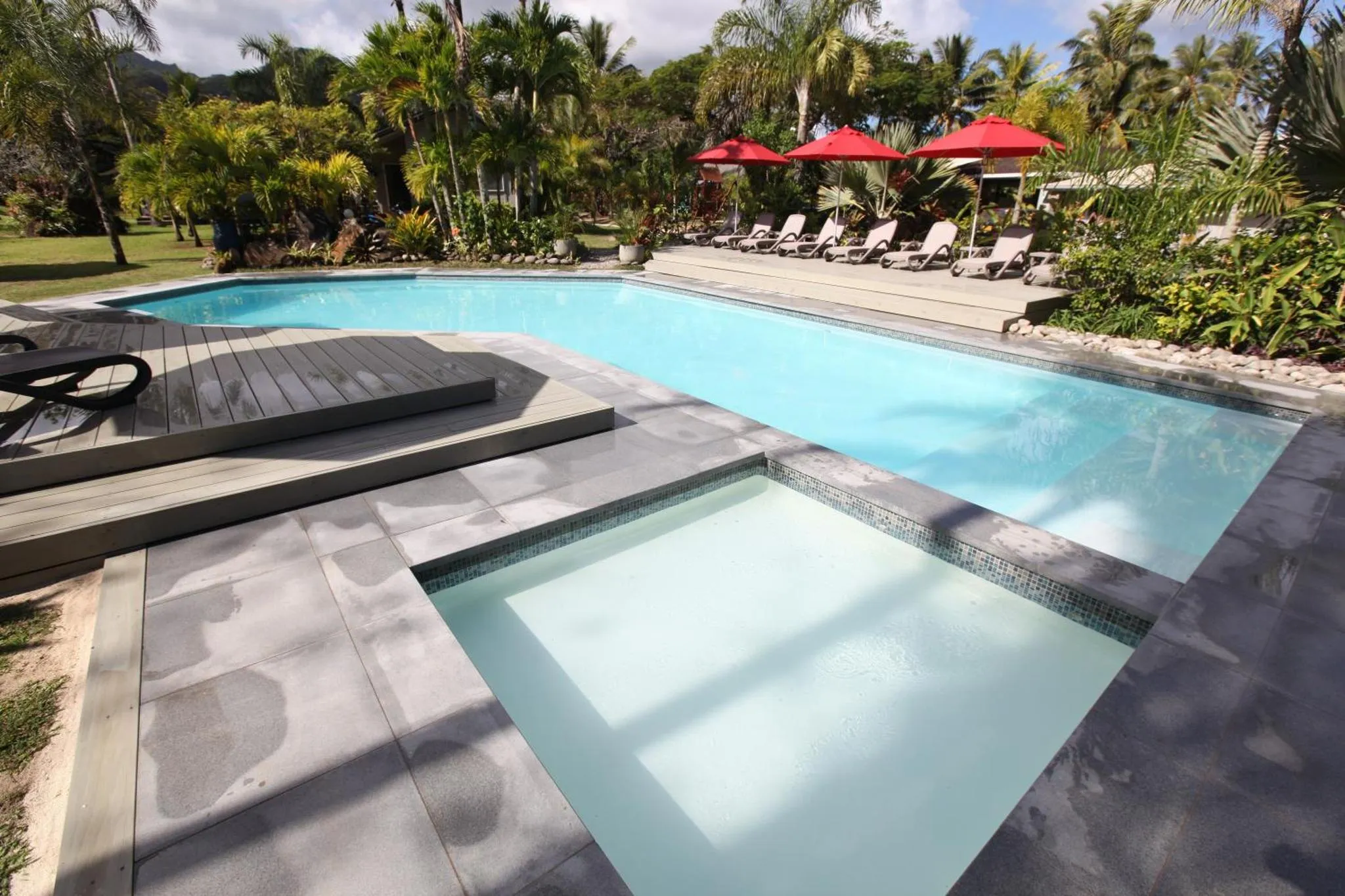 Une piscine rectangulaire avec un espace de détente aménagé sur une terrasse.