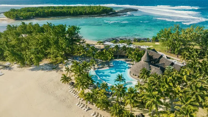 Vue aérienne d'un complexe hôtelier tropical avec piscine et plage.