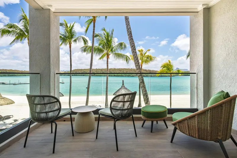 Terrasse avec mobilier d'extérieur donnant sur une plage de sable blanc et la mer.
