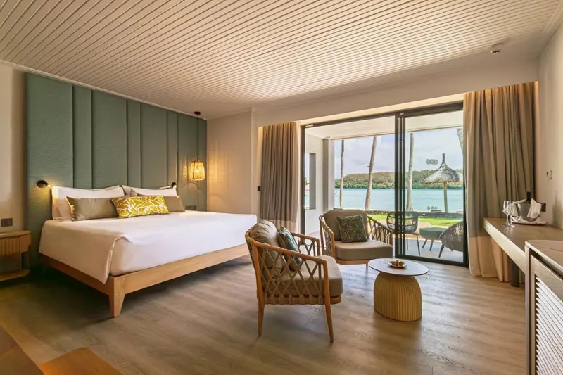 Une chambre lumineuse avec un grand lit et un coin salon donnant sur une vue extérieure.