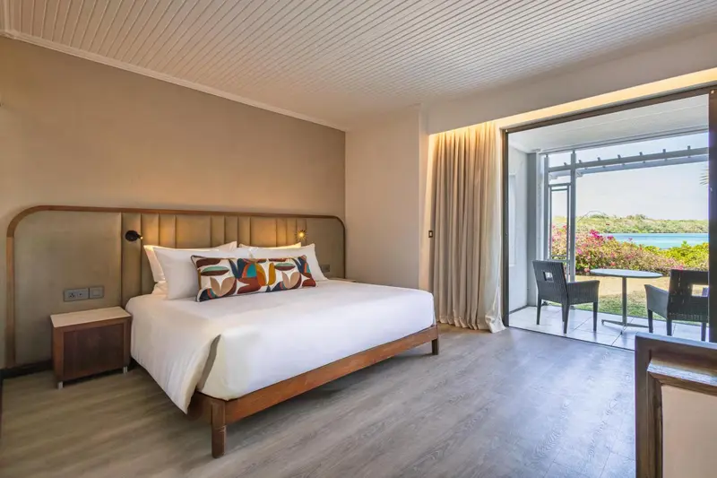 Une chambre lumineuse avec un grand lit et un accès à une terrasse.