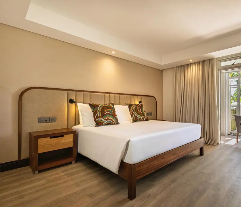 Une chambre lumineuse avec un grand lit et des oreillers décoratifs.