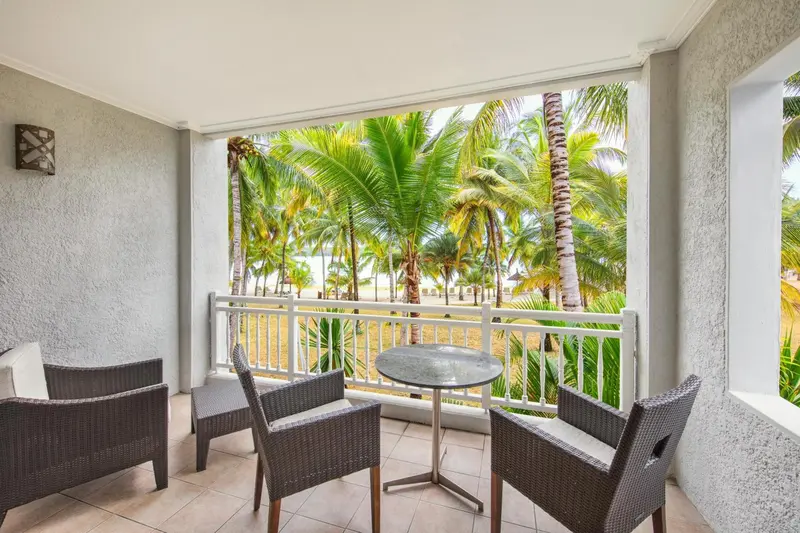 Terrasse aménagée avec mobilier de jardin donnant sur une végétation tropicale et la mer.