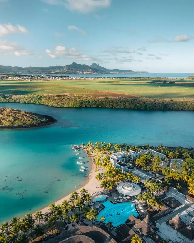 Vue aérienne d'une plage bordée de palmiers et d'un complexe hôtelier.